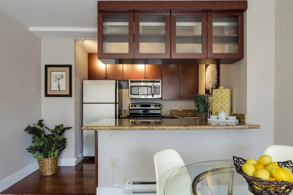 Apartment kitchen area with dark wood cabinets, stainless appliances, table with lemons in bow